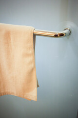 White towel hanging on the hotel bathroom glass door handle. Selective focus.