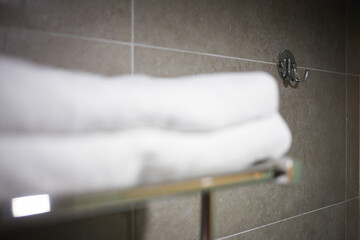 Clean white towel on a hanger. White bath towels near grey wall. Selective focus.