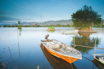Fototapeta premium Fisherman boat on the beautiful lake in the morning. Sunrise view.