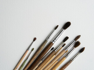 Fototapeta premium wooden watercolor brushes lie on a white canvas