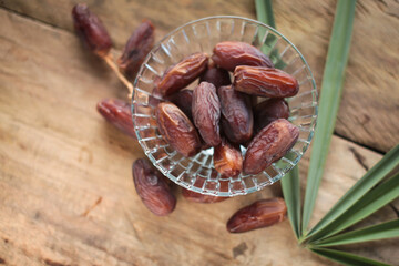 Date fruits in glass bowl on wooden background. Islamic food for iftar in Ramadhan.