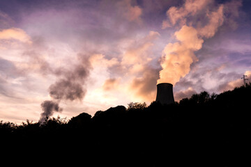 Silhouette of a cooling tower of a geothermal power plant at sunset, with pink-violet sky in...