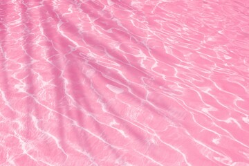 Palm leaf shadow on pink water wave texture background. Natural summer banner background	