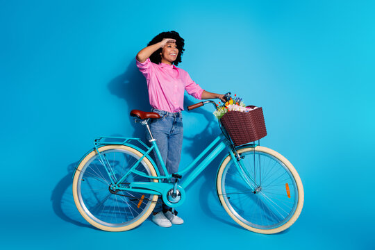 Full length photo of optimistic girl dressed silk shirt jeans hold bike look at long road empty space isolated on blue color background