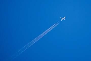 a plane flying towards the blue sky that leaves traces behind.