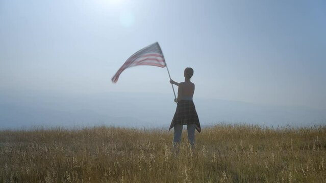 Young woman with American flag on top of hill