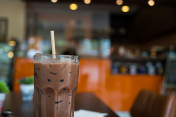 Iced chocolate milkshake drink in a glass with white paper straw
