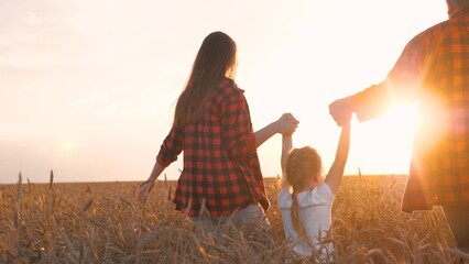 Mother father and daughter playing walking at sunset dry wheat field back view. Happy family running relaxing spending time together outdoor meadow sunny sky horizon enjoy freedom positive emotion