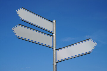Metal signpost with three arrows and sky in background