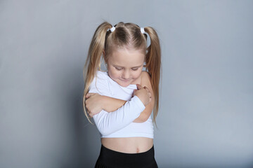 Young girl hugs herself, a shy smile on her face. Evokes self-love and the comfort found in one's...