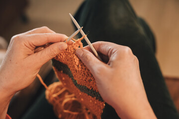 Close-up of the hands of an unrecognizable person knitting a sweater with two needles