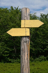 Wooden signpost with two yellow arrows - tourist trail