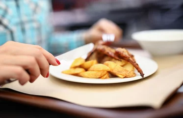  Woman hold knife and fork in her hand. White plate of potatoes and chicken on table. © H_Ko