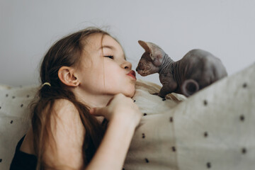 a sincere happy girl rejoices at the kitten she was given. The girl hugs and plays with a small and cute cat