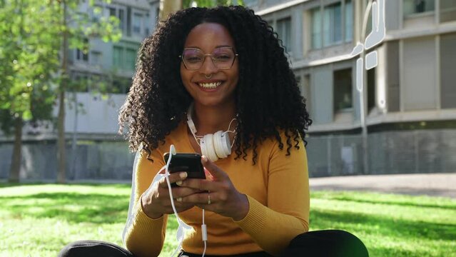 Young African American woman using smart mobile application smiling at camera 