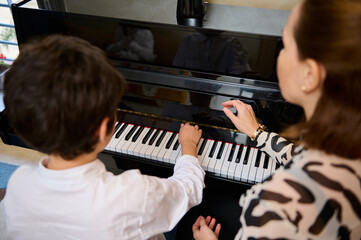 View from above of an adorable teen boy enjoying playing grand piano at home, creating music and...