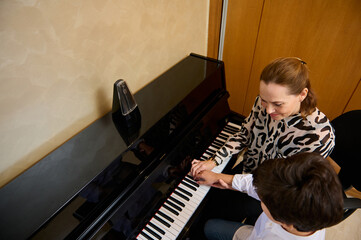 View from above of a Caucasian pleasant mature female music teacher, musician pianist teaching...