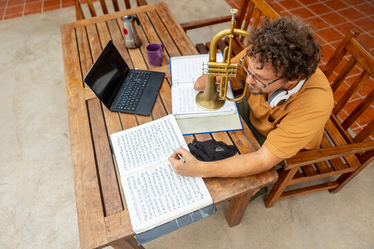 One-armed trumpeter composing music in a home courtyard