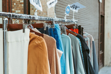 A range of discounted fashion items displayed on a clothes rack outside a store, with visible price signs attracting shoppers