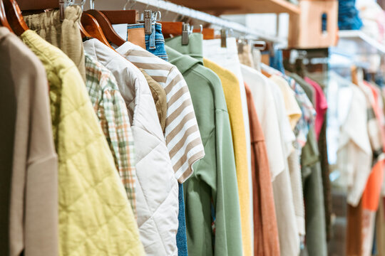A diverse collection of casual garments hangs neatly on a rack in a clothing shop, showcasing an array of colors and patterns