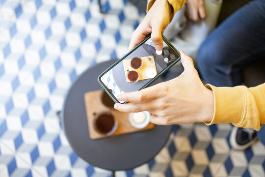 Anonymous person taking a photo of coffee with smartphone