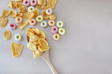 Top view of Corn Flakes in Spoon with Fruit Loops on Background