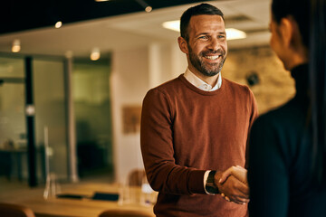 Smiling businessman shaking hands with a female colleague, at the office after finished meeting.