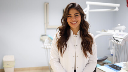 Portrait of a beautiful, young female dentist at her office - obrazy, fototapety, plakaty