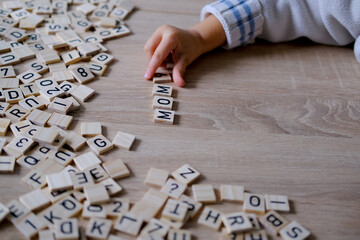 child's small hands carefully arrange wooden letters to spell Mom, heartwarming expression of love...