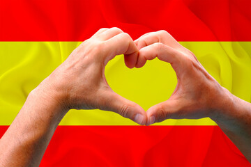 close-up of male hands in heart form against background of silk national flag of European state of...