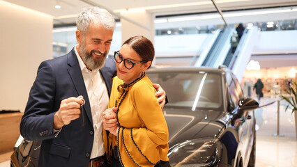 Happy mature couple just bought their new car at the car salon
