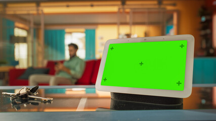 Creative Smart Home Device with Green Screen Display. In the Background Person using Smartphone to...