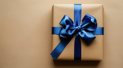 box wrapped in brown paper and tied with a blue silk ribbon with a bow, gift on a beige background, top view, gift box with blue ribbon, background. Top view. Copy space
