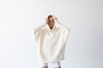 Beautiful blonde woman posing in white hoodie and leggings posing against white background