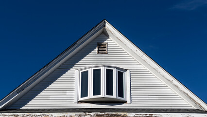 Old house attic bow window and small air vent against clear blue sky in Boston, Massachusetts, USA