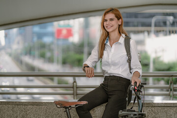 Eco friendly vehicle, businesswoman ride bicycle in urban downtown to reduce carbon footprint. Mixed race woman environmentalist person commuting with bicycling, alternative transport to green energy.