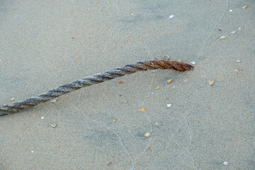 A thick rope used for mooring boats on the beach sunk in the sand