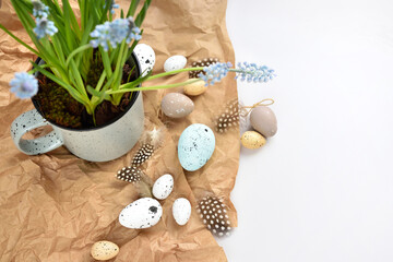 Easter eggs and light blue muscari flowers in cup on a white table. Easter still life. Top view - 775862165