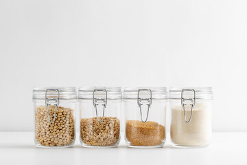 food storage, culinary and storage concept - jars with oat flakes, semolina, couscous and beans on...