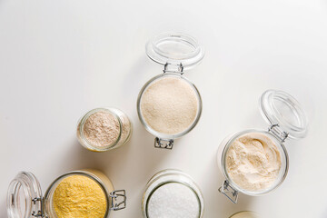 food storage, culinary and eating concept - close up of jars with different kind of flour and salt on white background, top view
