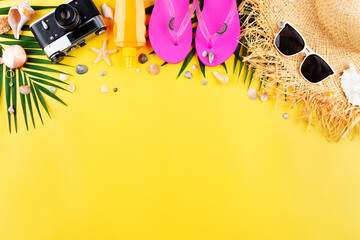 Vacation planning simple theme of chillout attributes - straw hat sunglasses flip flops film camera and palm leaves on uniform yellow background flat lay with copy-space