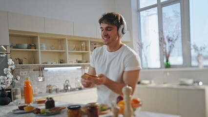 Funny man dancing cooking in headphones at kitchen close up. Guy listening music