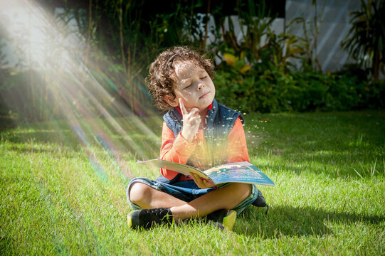 Criança sentada no gramado lendo um livro, pensativo com raios de sol ao fundo, cenário ludico infantil