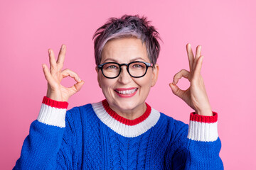 Photo of nice aged lady demonstrate okey symbol wear blue sweater isolated on pink color background
