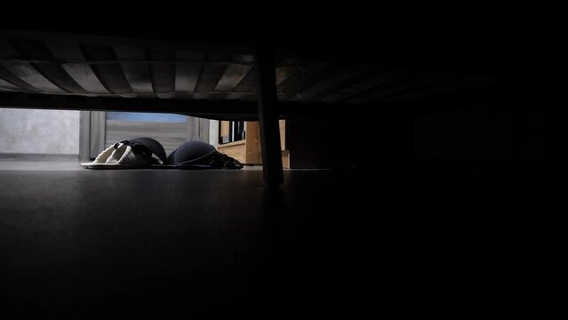 View from under wobbly bed where couple makes love. Someone undresses woman and throws her underwear on floor next to bed. Woman's bra falls onto slippers. Man and woman have sex.