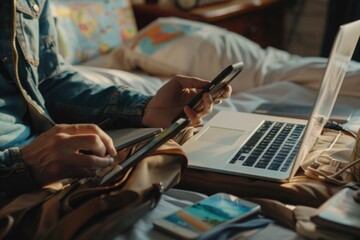 A person sitting on a bed with a laptop and cell phone. Ideal for technology and work from home concepts - obrazy, fototapety, plakaty