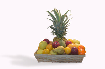 basket with assorted fruits in which a pineapple stands out, isolated on white background