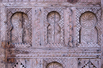 background with carved wood forming geometric elements and horseshoe arches