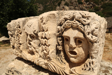 Stone with elaborate ancient relief of three theater masks in the ancient town of Myra, near Demre, Turkey