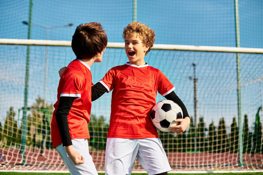 Two young men in athletic wear standing side by side on a soccer field, displaying teamwork and camaraderie.